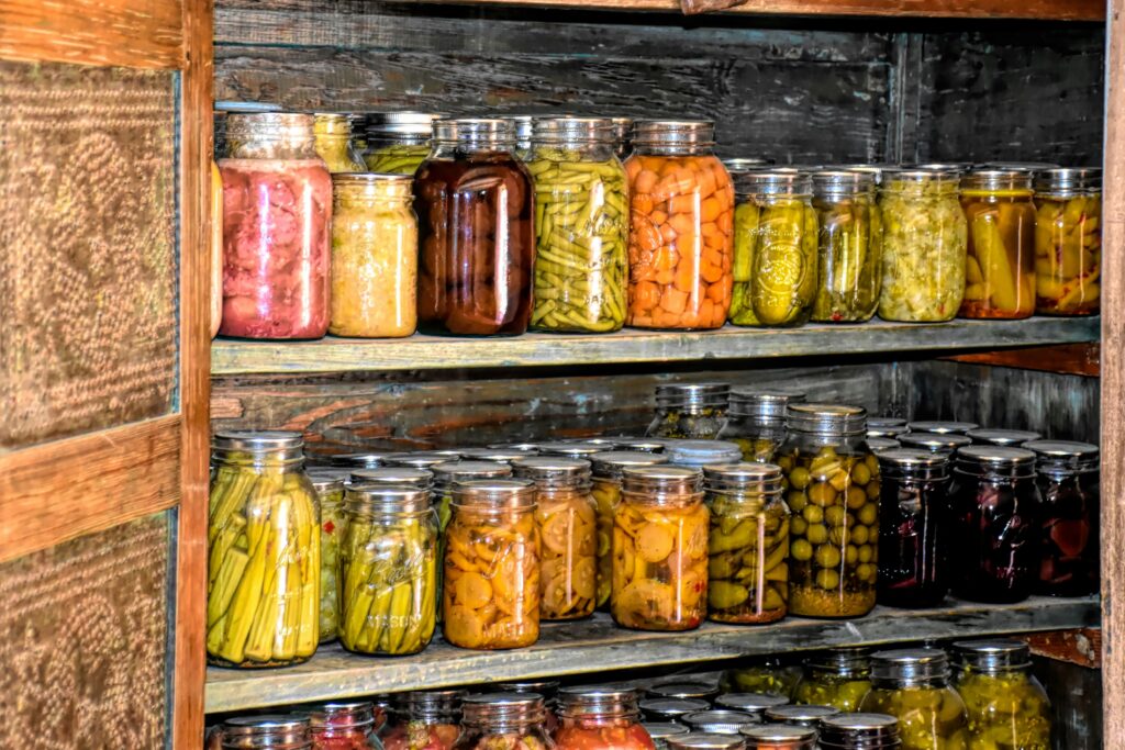 Various sized mason jars with vegitables being stored in the cubbard.