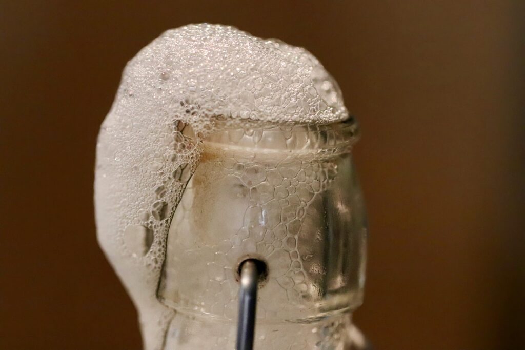 Overflowing ferment bottle with foam bubbling out of the top
