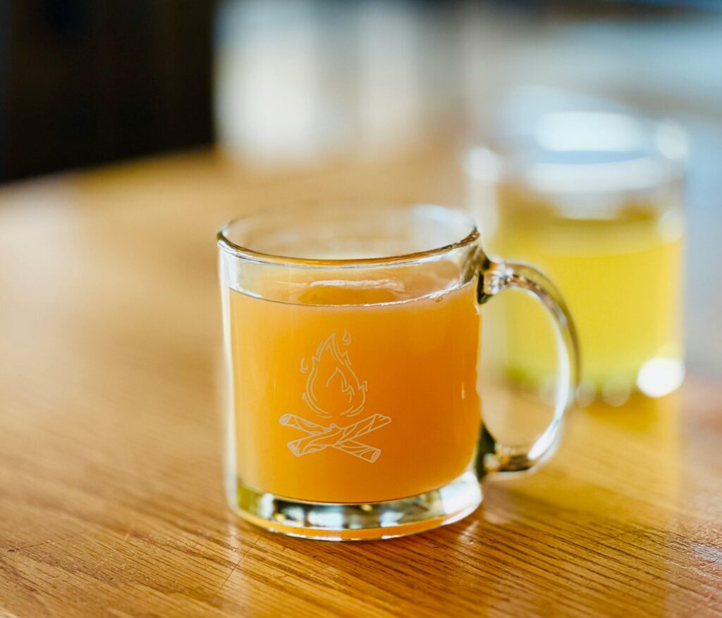 Jar of fire cider with chopped roots and peppers on a wooden board. One of the best fermented remedies for cold and flu season