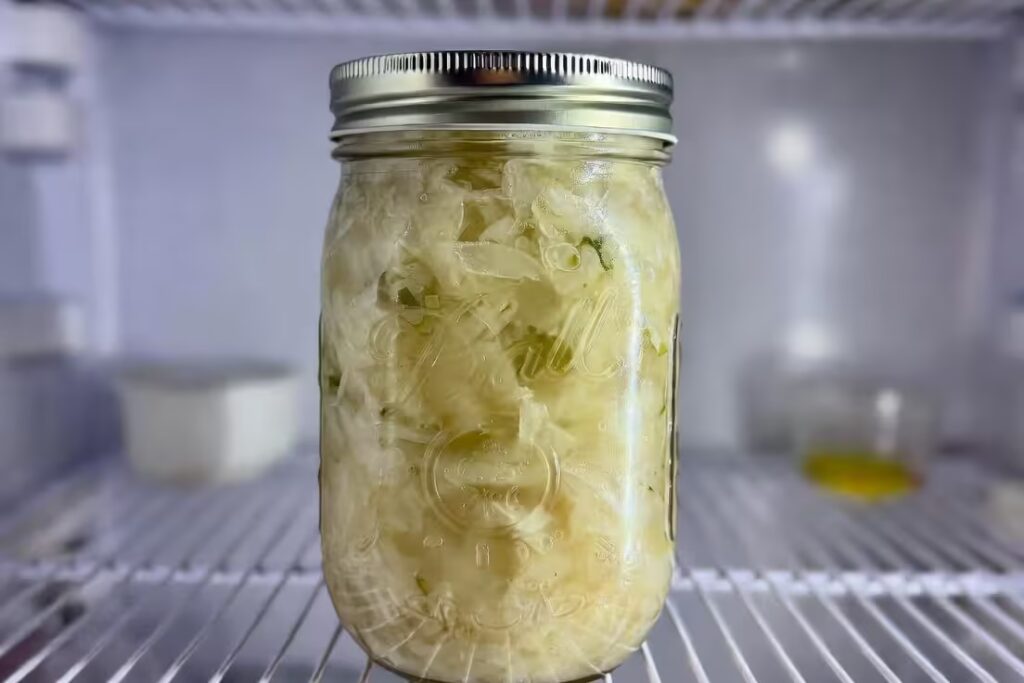 jar of sauerkraut stored in refrigerator with brine