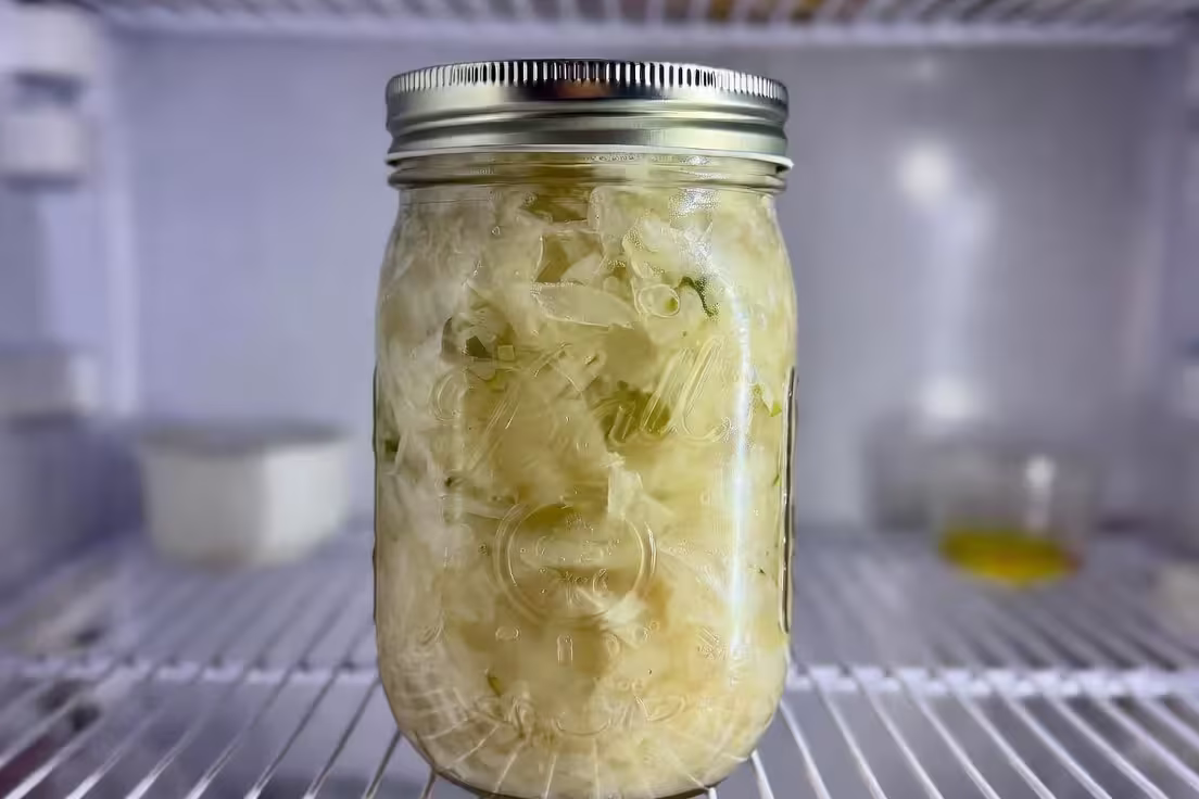 jar of sauerkraut stored in refrigerator with brine